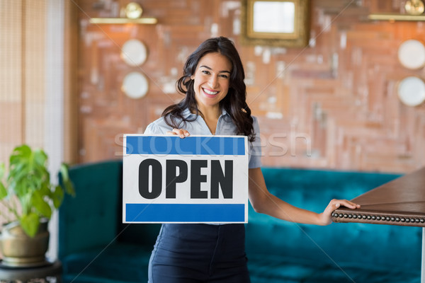 Smiling waitress holding a board with open sign in restaurant Stock photo © wavebreak_media