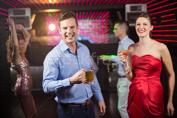 Smiling couple holding glass of beer and cocktail while dancing Stock photo © wavebreak_media