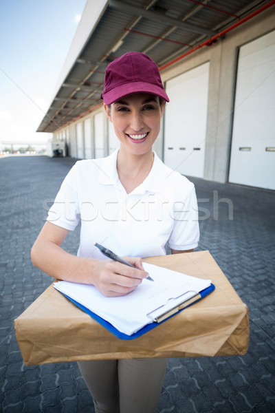 Portrait of delivery woman holding a clipboard and parcel Stock photo © wavebreak_media