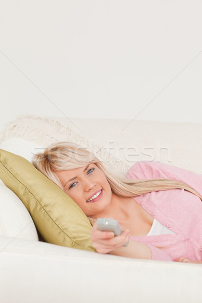 Attractive blonde woman posing while lying on a sofa in the living room Stock photo © wavebreak_media