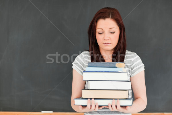 Stock photo: Beautiful woman bringing cumbersome books in a classroom