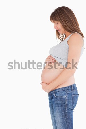 Side view of an attractive pregnant woman caressing her belly while standing against a white backgro Stock photo © wavebreak_media