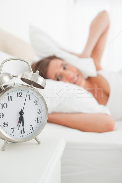The focus on the clock as it rings causing the girl to cover her ears with a pillow. Stock photo © wavebreak_media