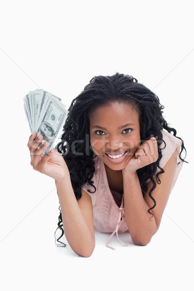 A young woman holding American dollars is resting her head on her hand against a white background Stock photo © wavebreak_media