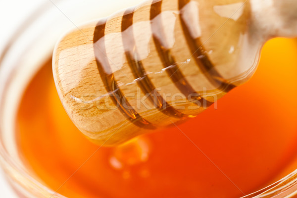 Honey dipper outgoing a honey bowl against a white background Stock photo © wavebreak_media