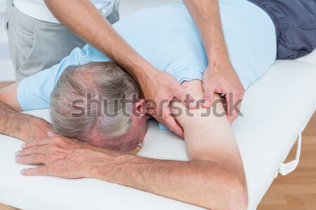 Doctor manipulating the side of the head of his patient in a room Stock photo © wavebreak_media