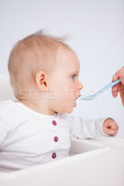 Beautiful little girl being fed with a spoon against a grey background Stock photo © wavebreak_media