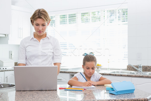 Foto stock: Little · girl · lição · de · casa · mãe · usando · laptop · casa · cozinha