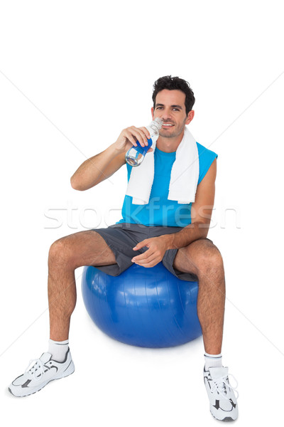 Fit man sitting on exercise ball while drinking water Stock photo © wavebreak_media