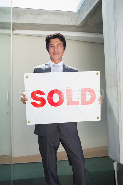 Confident estate agent standing at front door showing sold sign Stock photo © wavebreak_media