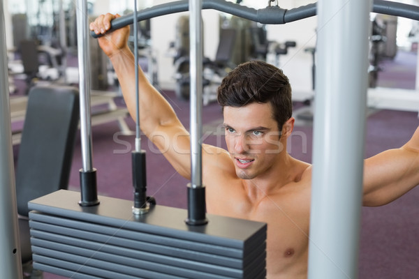 Stock photo: Muscular man exercising on a lat machine in gym
