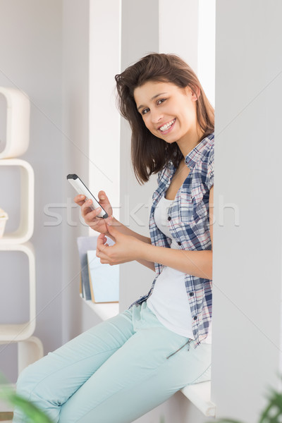 Pretty brunette sitting beside her window sending a text Stock photo © wavebreak_media