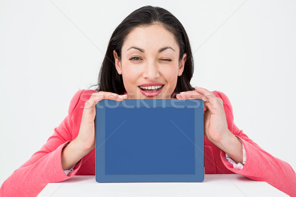 Elegant brunette showing tablet and winking Stock photo © wavebreak_media
