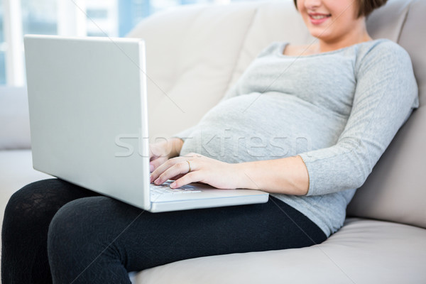Foto d'archivio: Donna · incinta · utilizzando · il · computer · portatile · home · seduta · divano · donna