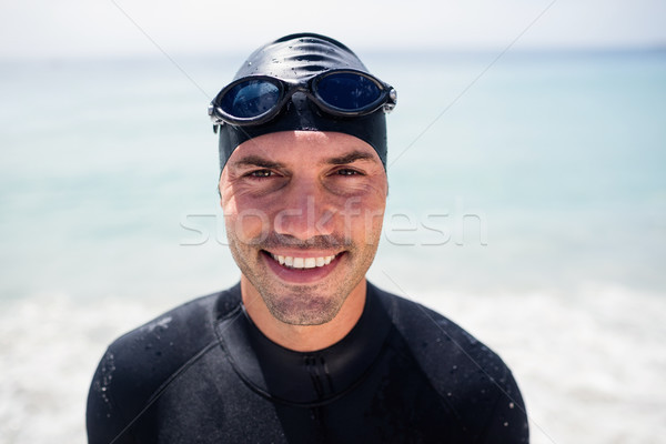 Young man in wetsuit and swimming goggles standing on beach Stock photo © wavebreak_media