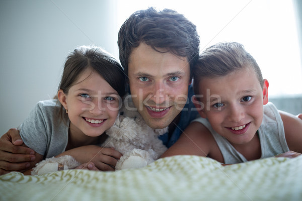 Portrait of father lying with their kids in bedroom Stock photo © wavebreak_media