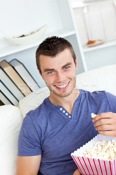 Laughing caucasian man eating popcorn looking at the camera in the living-room Stock photo © wavebreak_media