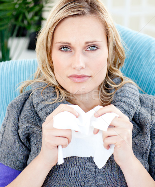 Stock photo: Diseased woman using a tissue sitting on a sofa