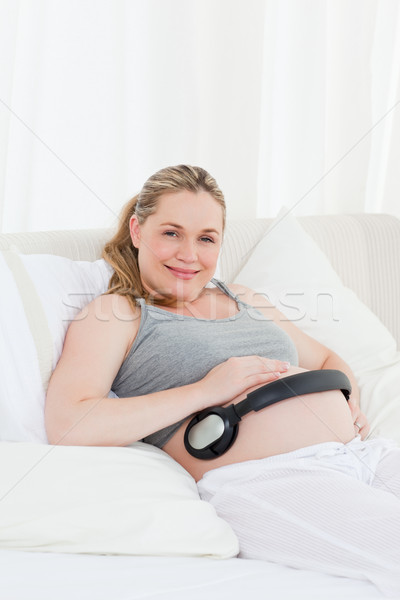 Pregnant woman putting her earphones on her belly at home Stock photo © wavebreak_media