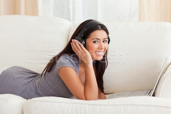 Mosolygó nő fülhallgató kanapé néz kamera nappali Stock fotó © wavebreak_media