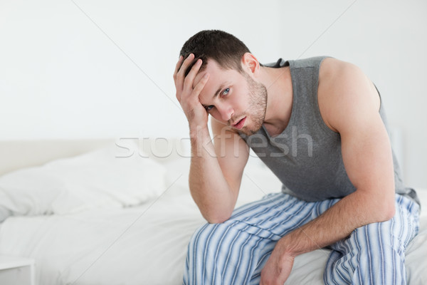 Jeune homme séance lit regarder caméra maison [[stock_photo]] © wavebreak_media