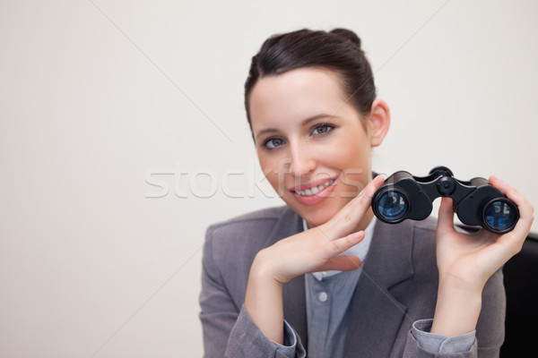 Smiling young businesswoman with binoculars Stock photo © wavebreak_media