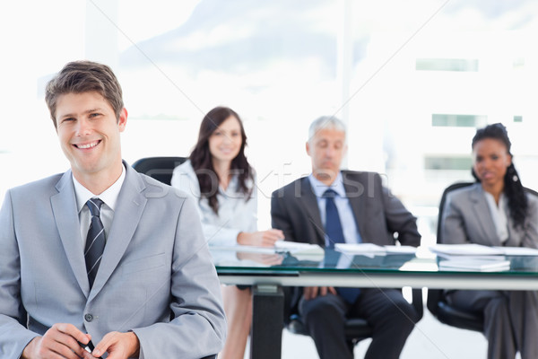 Smiling executive sitting in front of his earnest team and looking at the camera Stock photo © wavebreak_media