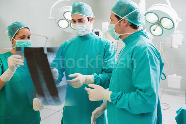 Stock photo: Close up of a surgical team talking about a X-ray in an operating theatre