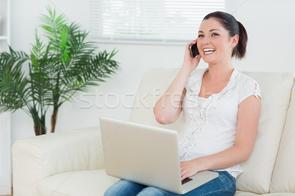 笑 女子 坐在 榻 客廳 使用筆記本電腦 商業照片 © wavebreak_media