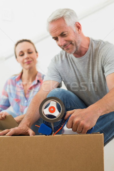 Happy couple sealing cardboard moving boxes Stock photo © wavebreak_media