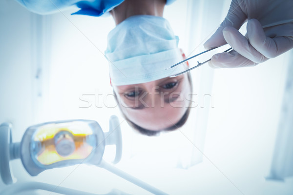 Female dentist in surgical mask holding dental tool Stock photo © wavebreak_media
