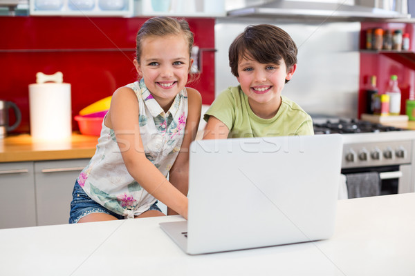 Smiling siblings using laptop in kitchen Stock photo © wavebreak_media