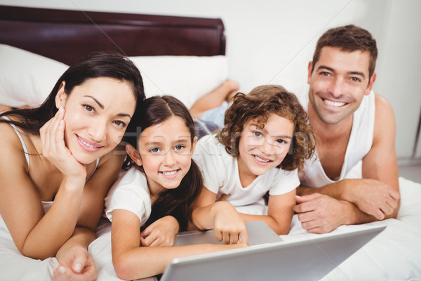 Portrait of happy children with parents using laptop on bed Stock photo © wavebreak_media