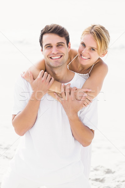 Stock photo: Man giving a piggy back to woman on the beach