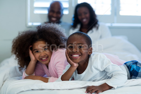 Children lying on bed with parents in background Stock photo © wavebreak_media