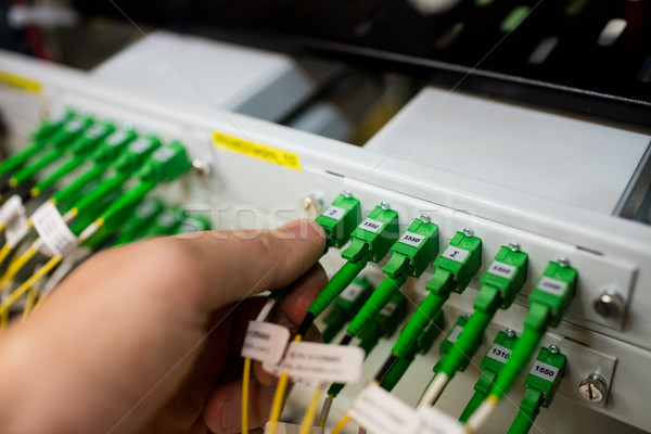 Stock photo: Technician plugging patch cable in a rack mounted server