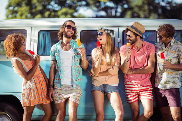Group of happy friends standing with ice lolly in front of camper van Stock photo © wavebreak_media
