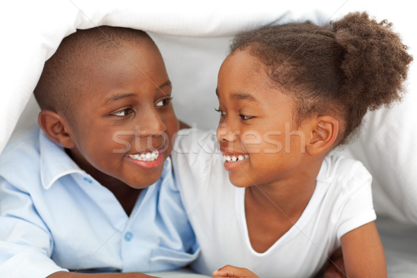 Portrait of laughing siblings lying down on bed Stock photo © wavebreak_media