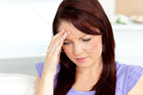 Stock photo: Caucasian woman with a headache sitting on a sofa at home in the living-room