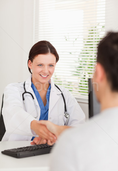 Stock photo: A female doctor is shaking hands with a patient