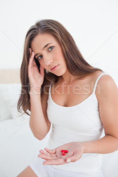 The woman has her hand on her head wondering about the pills and offering them. Stock photo © wavebreak_media