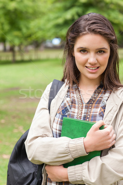 Portrait of a cute first-year student holding a textbook while posing in a park Stock photo © wavebreak_media