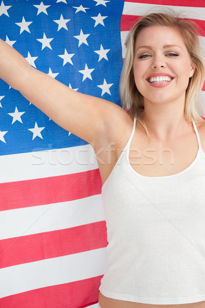 Cheerful blonde woman raising the Stars and Stripes flag in a studio Stock photo © wavebreak_media