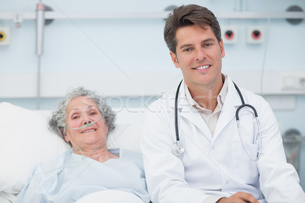 Doctor sitting on the bed next to a patient in hospital ward Stock photo © wavebreak_media