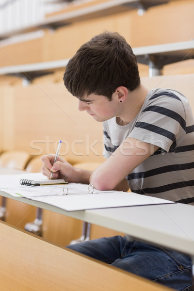 Stock photo: Concentrated student sitting at the lecture hall while writing