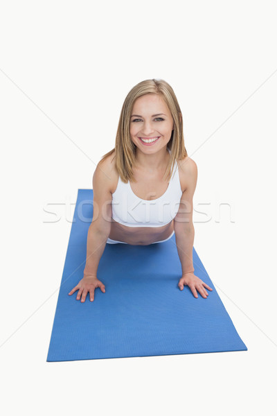 Stock photo: Portrait of happy woman doing push-ups on exercise mat