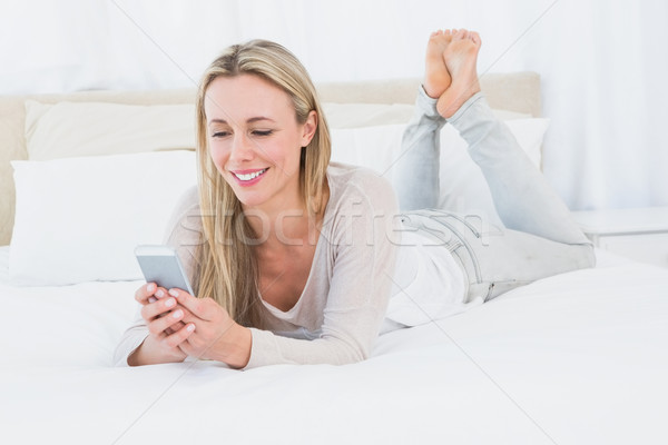 Smiling blonde using smartphone on the bed Stock photo © wavebreak_media