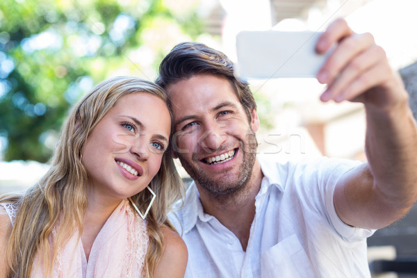 Smiling couple sitting and taking selfies Stock photo © wavebreak_media