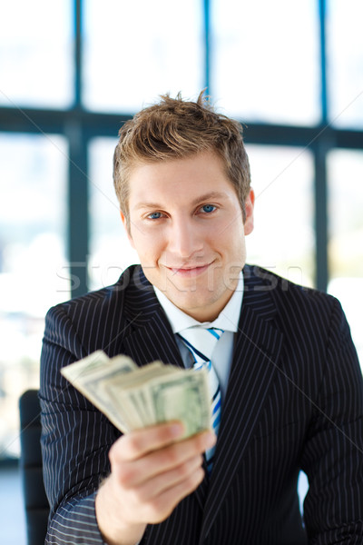 Junior businessman holding dollars and looking to the camera Stock photo © wavebreak_media