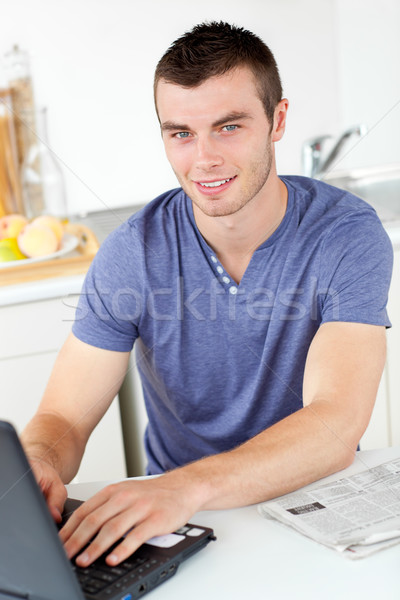 Handsome young man using his laptop looking at the camera in the kitchen Stock photo © wavebreak_media